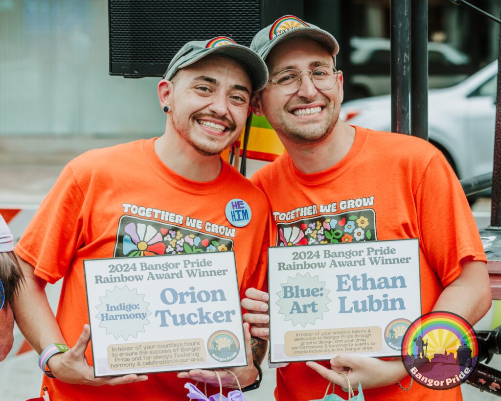 Ethan and Orion smiling holding their respective rainbow awards